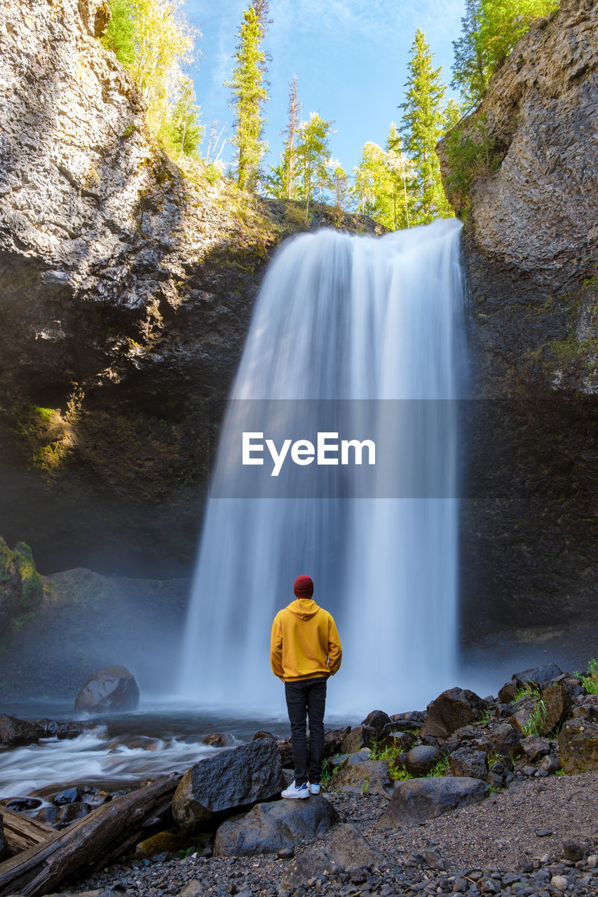 rear view of man looking at waterfall