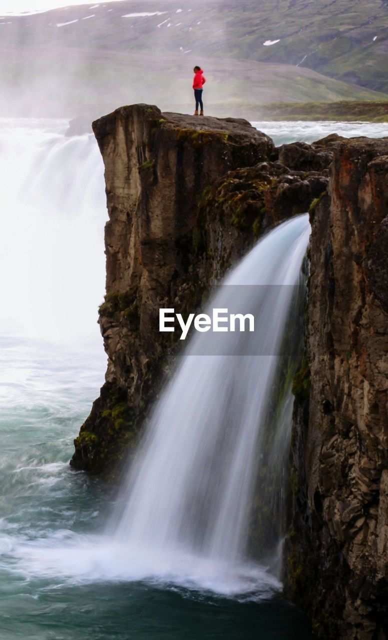 SCENIC VIEW OF WATERFALL AGAINST CLIFF