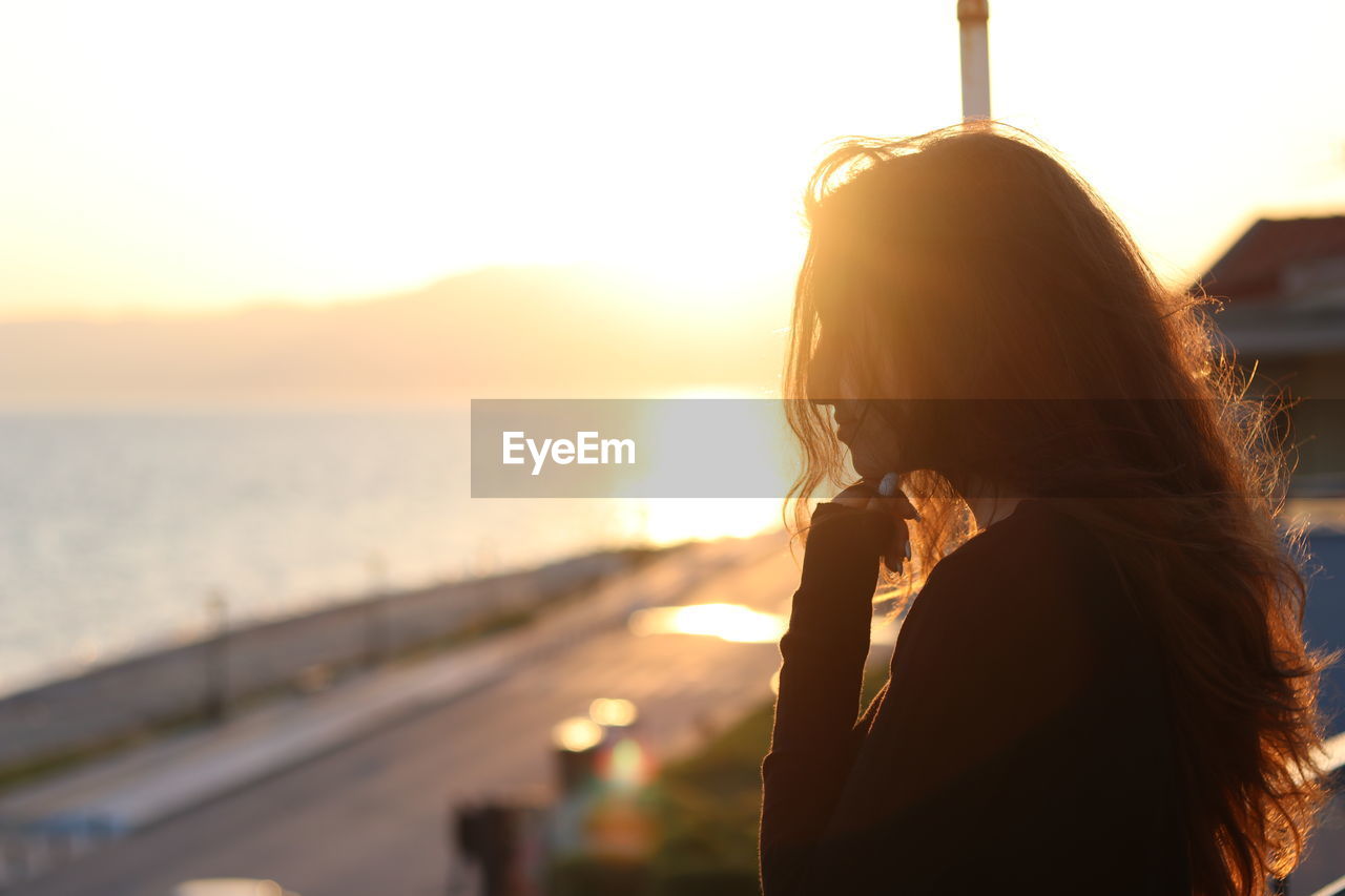 Side view of woman against sky during sunset