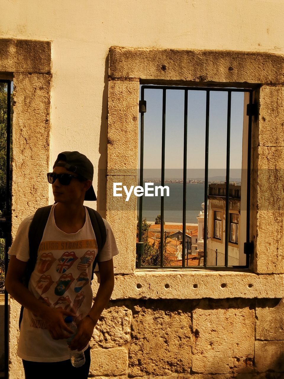 Young man standing by windows on wall