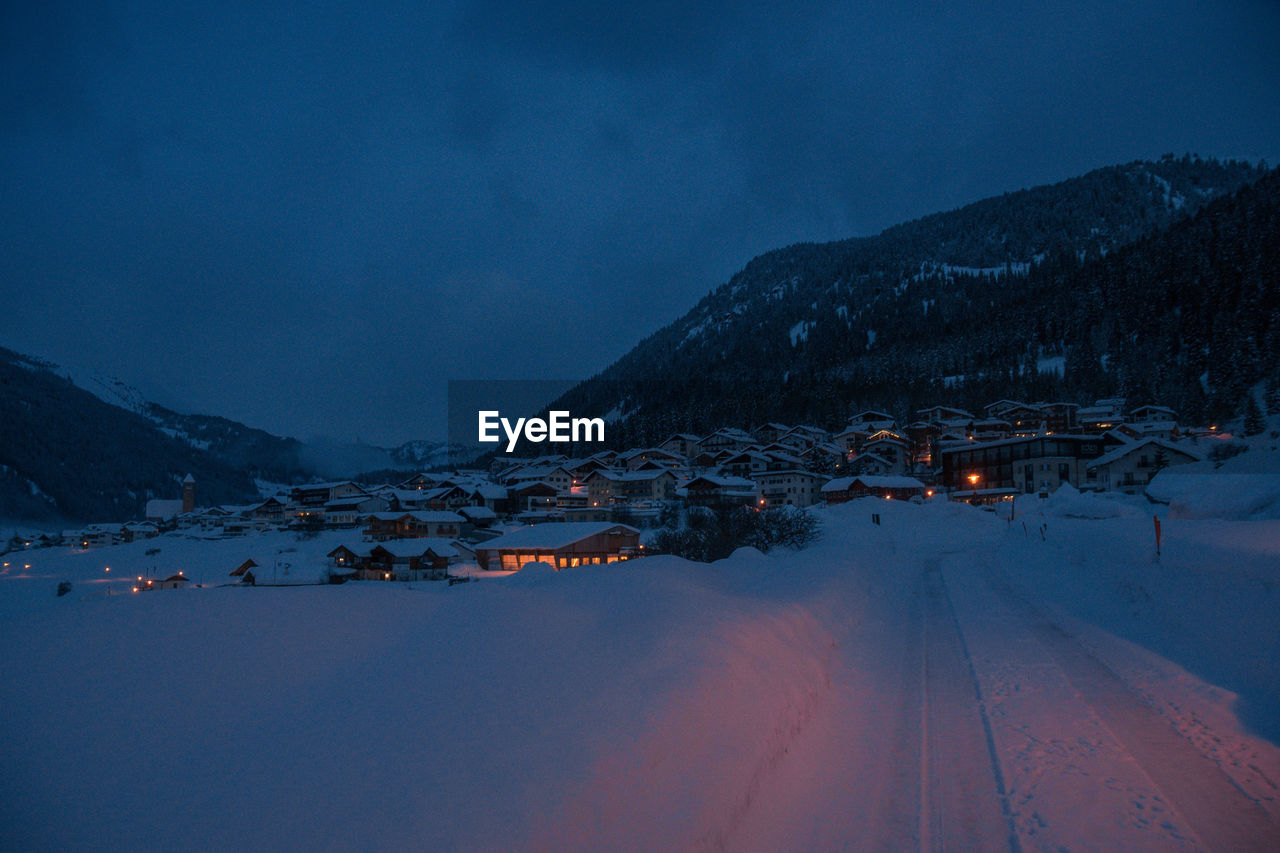 Houses by mountains against sky at night during winter