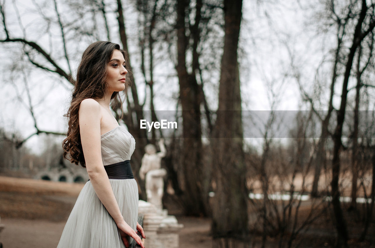 Side view of woman standing in forest