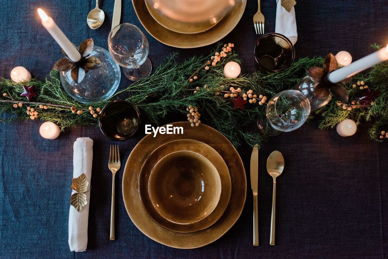 Sky view of a modern dinner table setting with candles and greenery