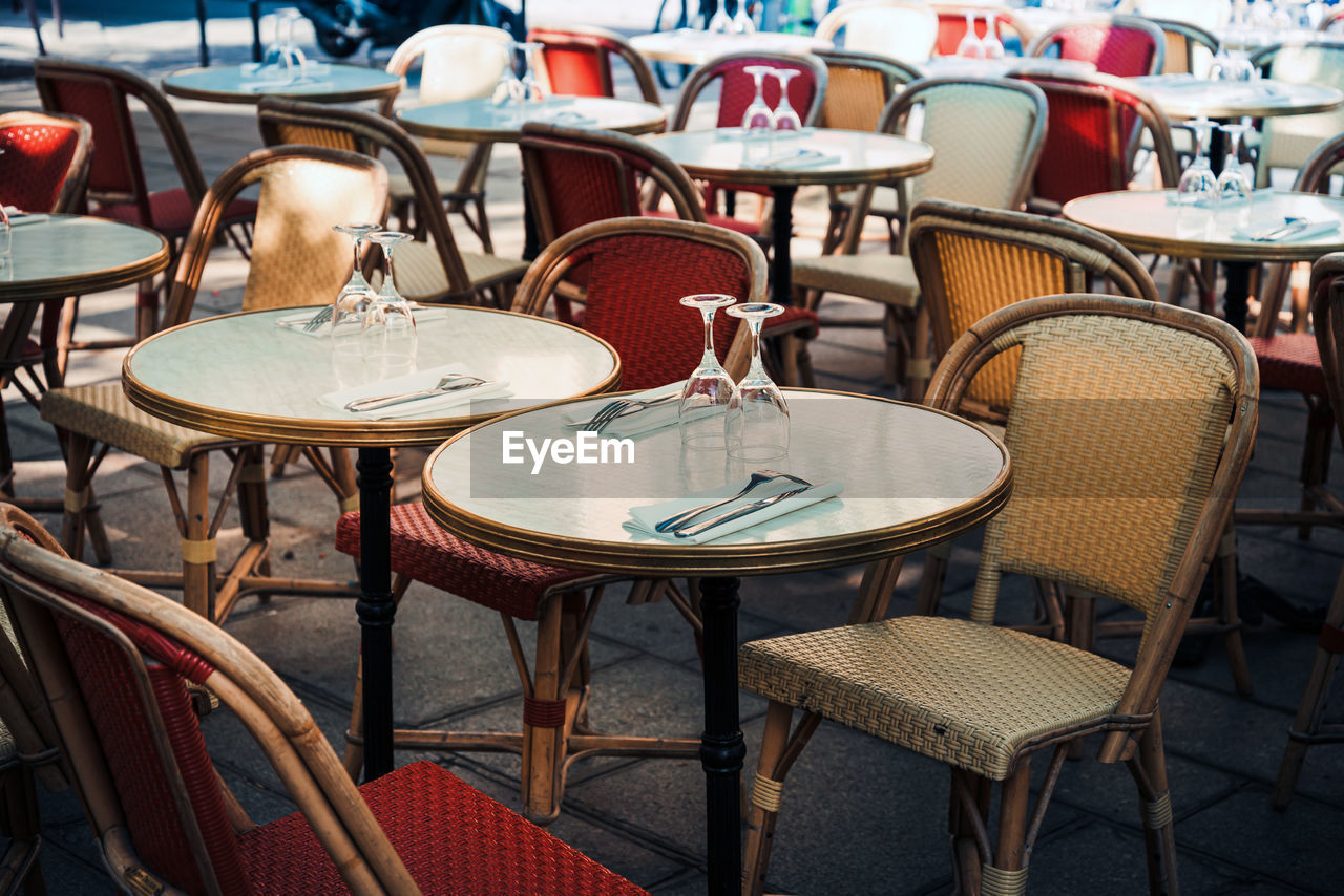 Empty chairs and tables at sidewalk cafe