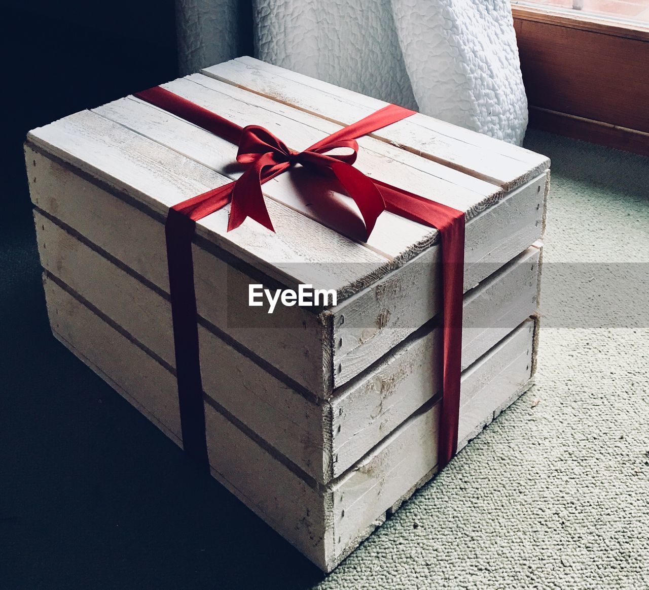 Close-up of ribbon tied wooden gift container on carpet