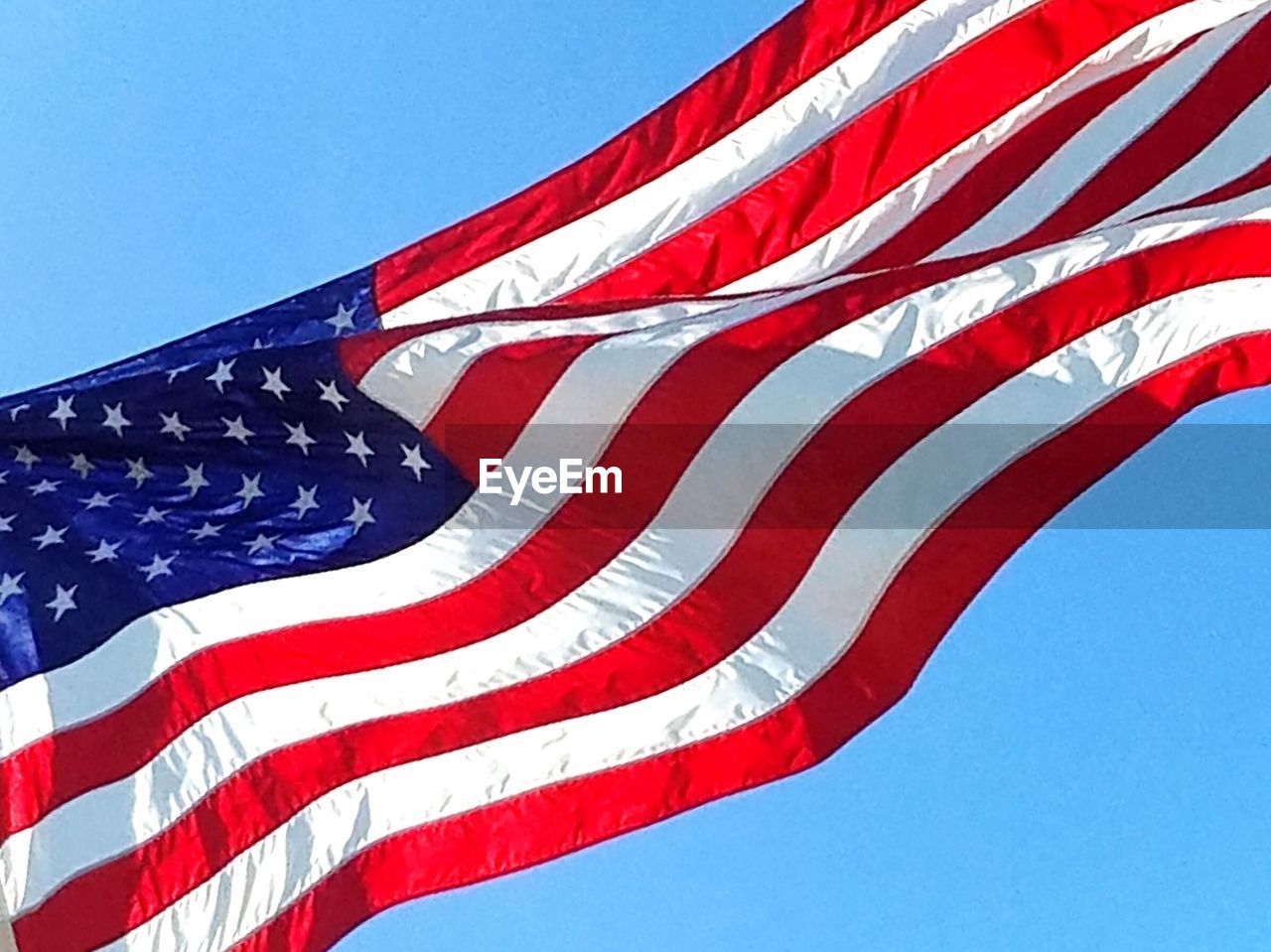 Low angle view of american flag against clear blue sky