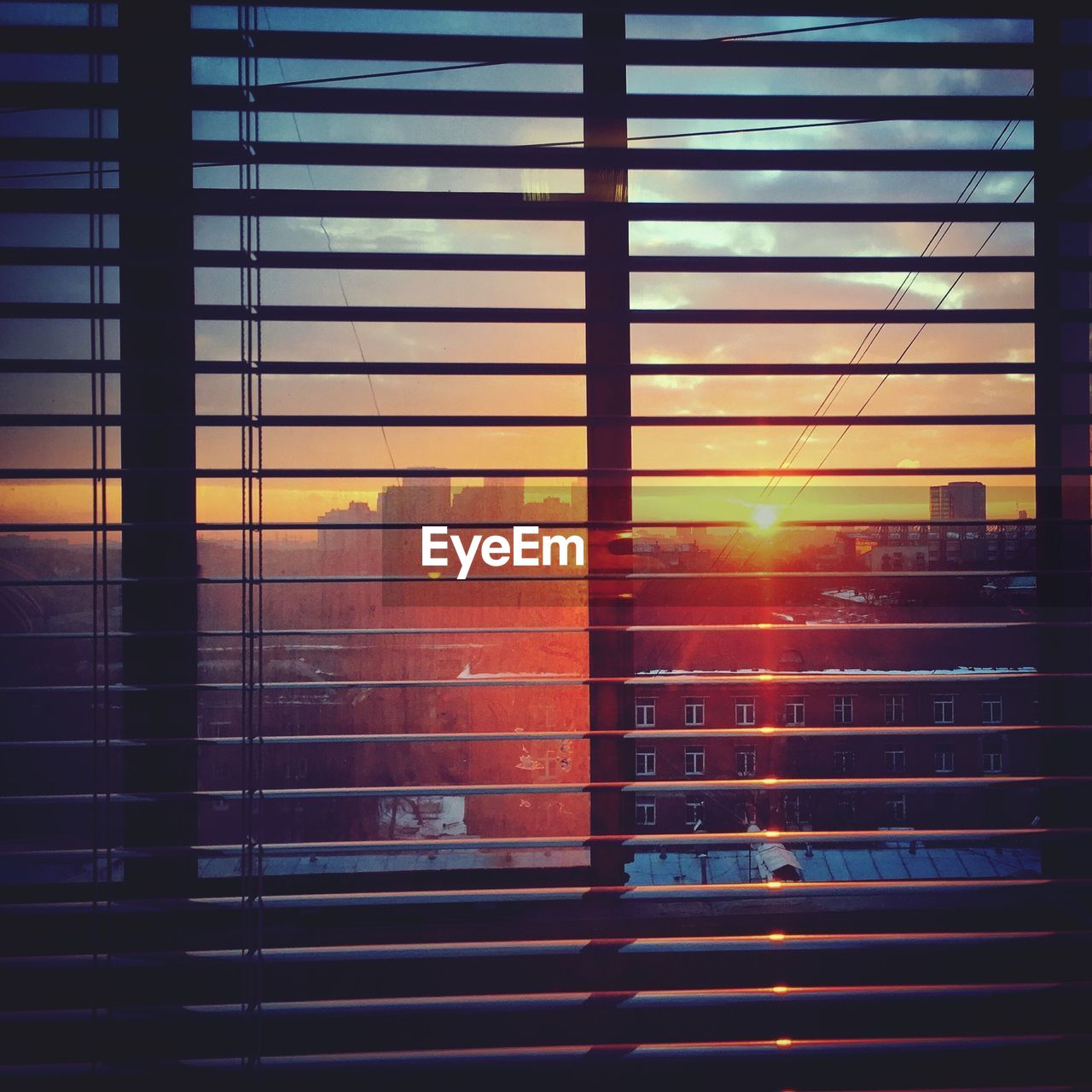 Close-up of window against city during sunset