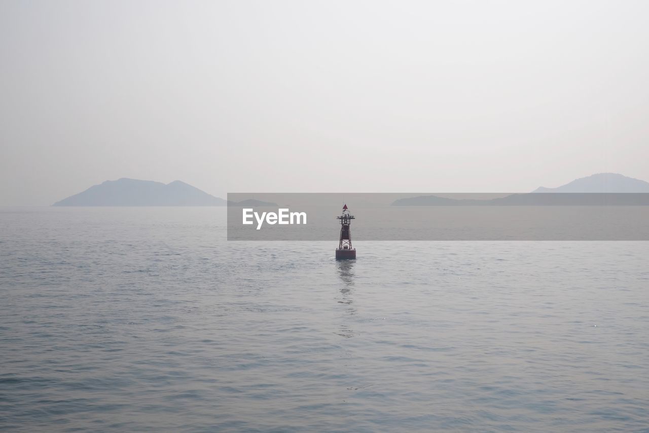 Buoy amidst sea against clear sky