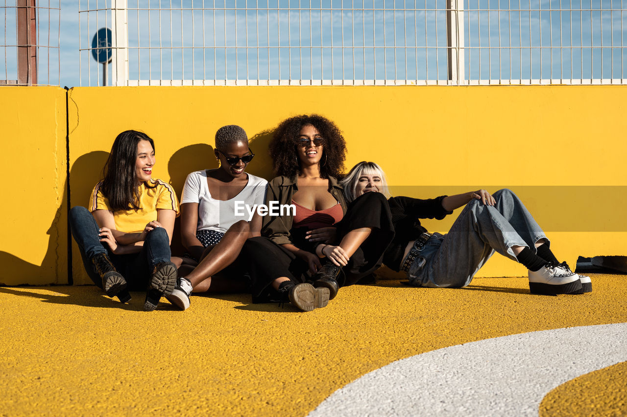 Cheerful young multiracial female students enjoying pastime on stadium