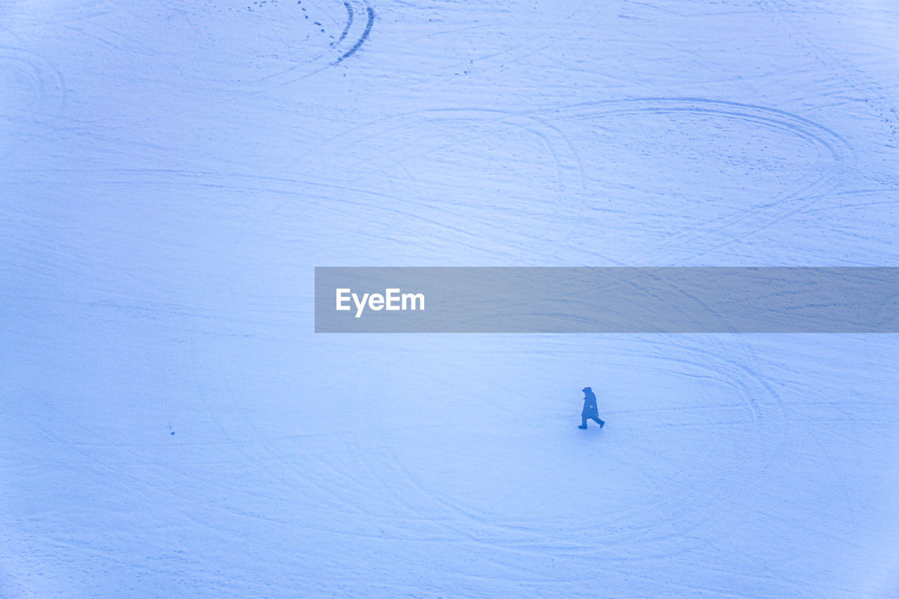 HIGH ANGLE VIEW OF PERSON SKIING ON SNOW COVERED LAND