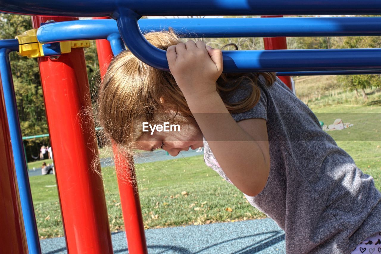 Smiling cute girl playing on play equipment at park