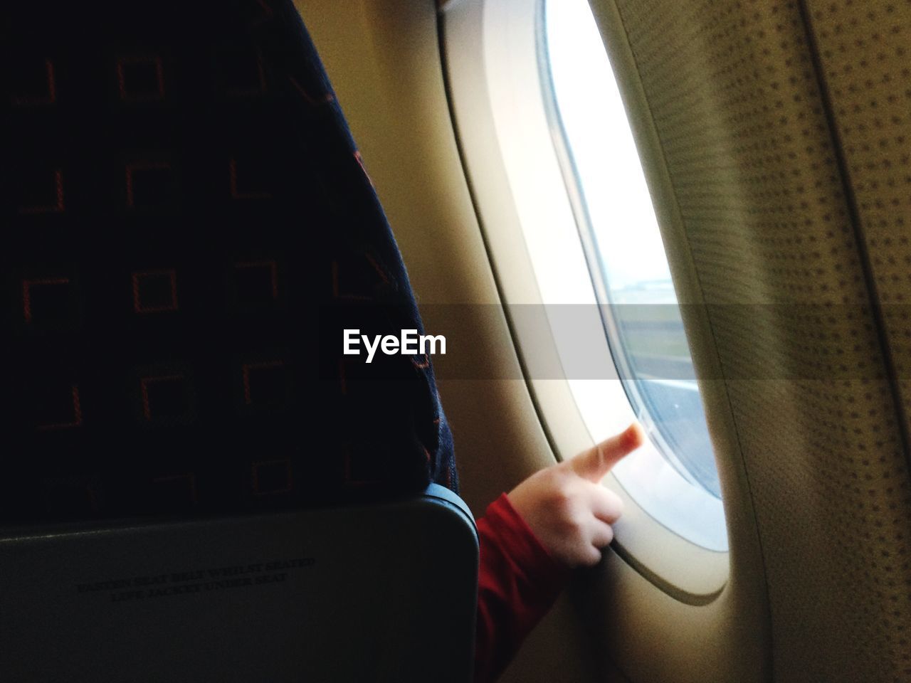 Cropped image of child touching airplane window