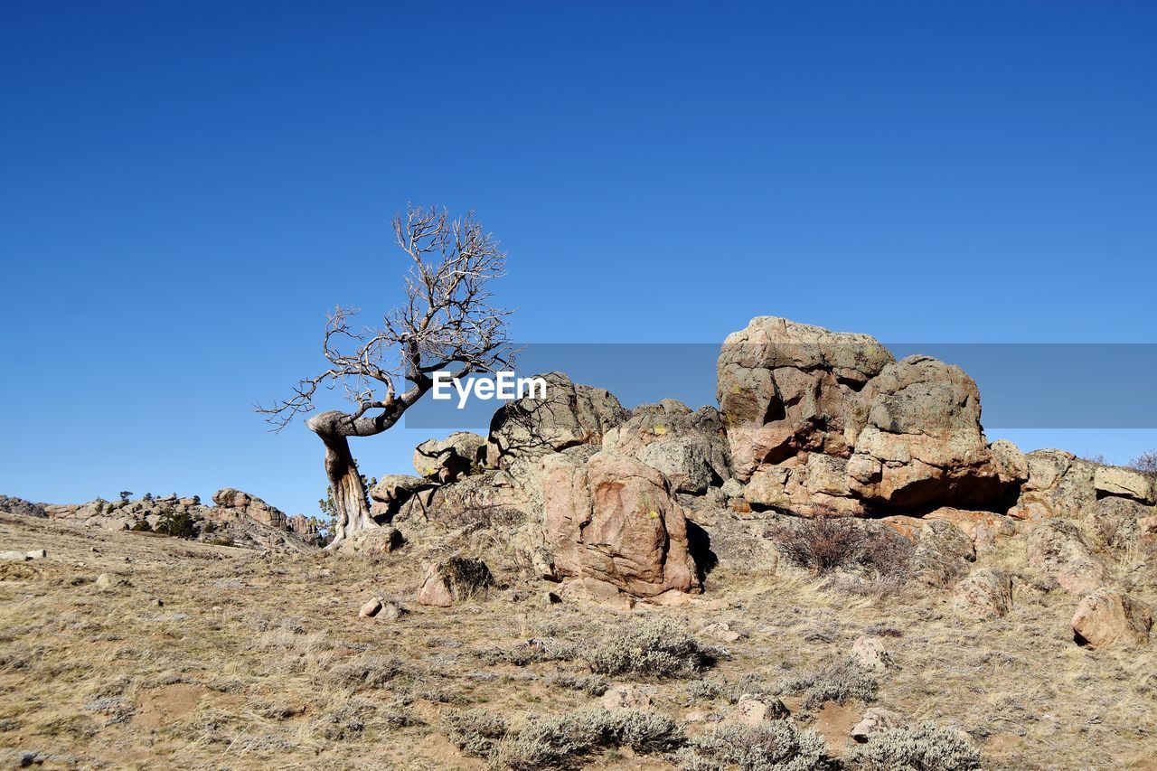 Rock formations on landscape against clear blue sky