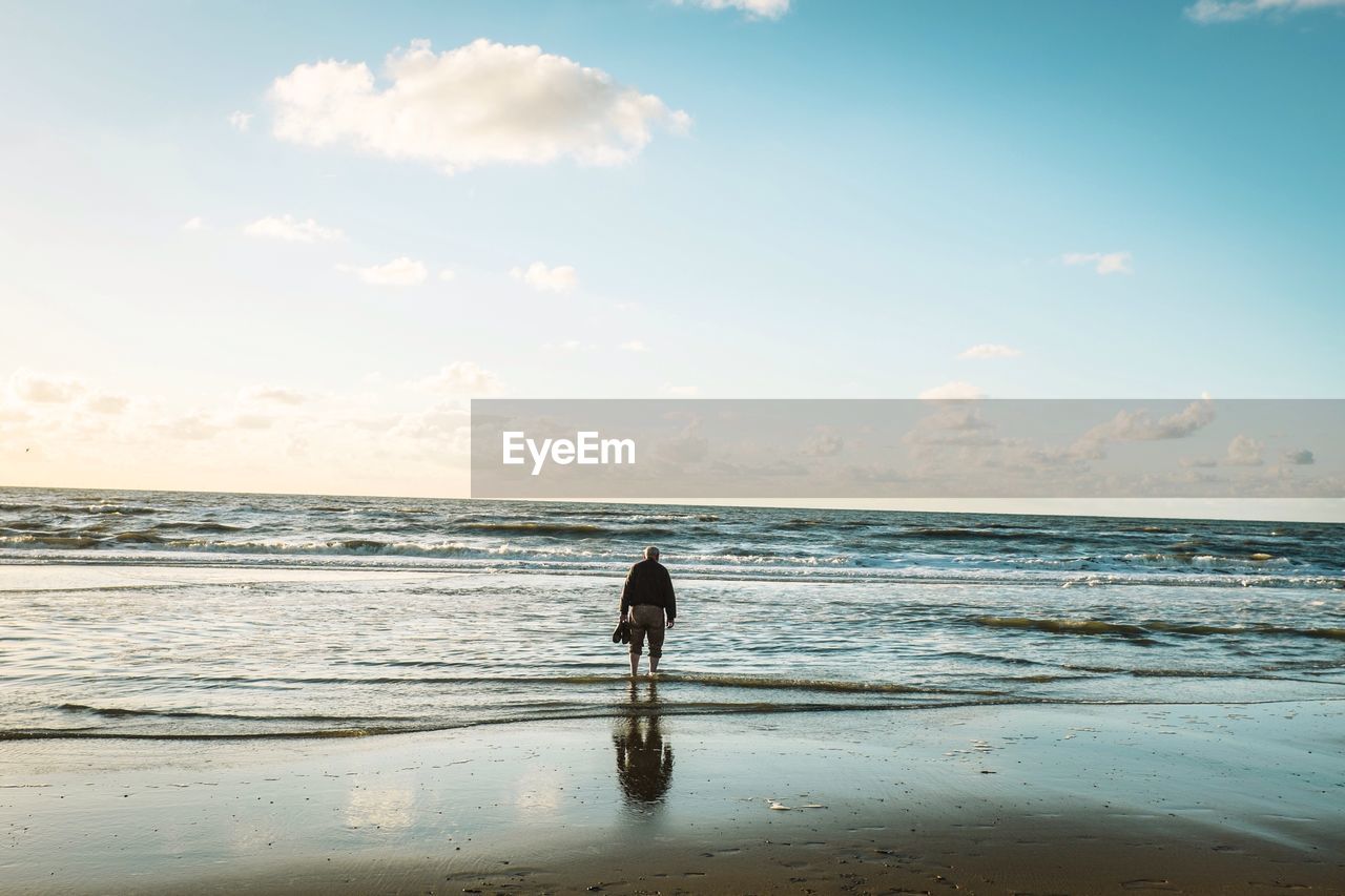 Rear view of man standing on sea shore