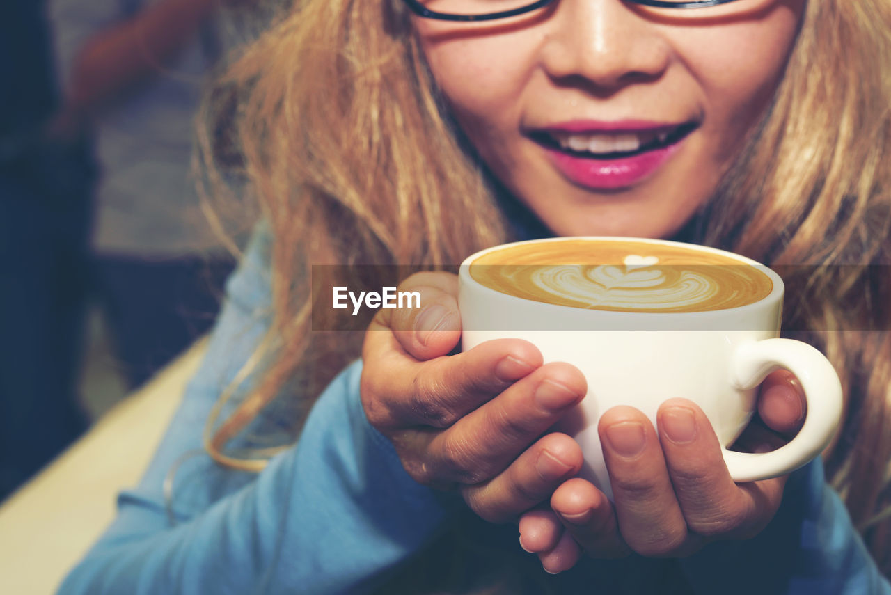 Midsection of woman holding cup of coffee