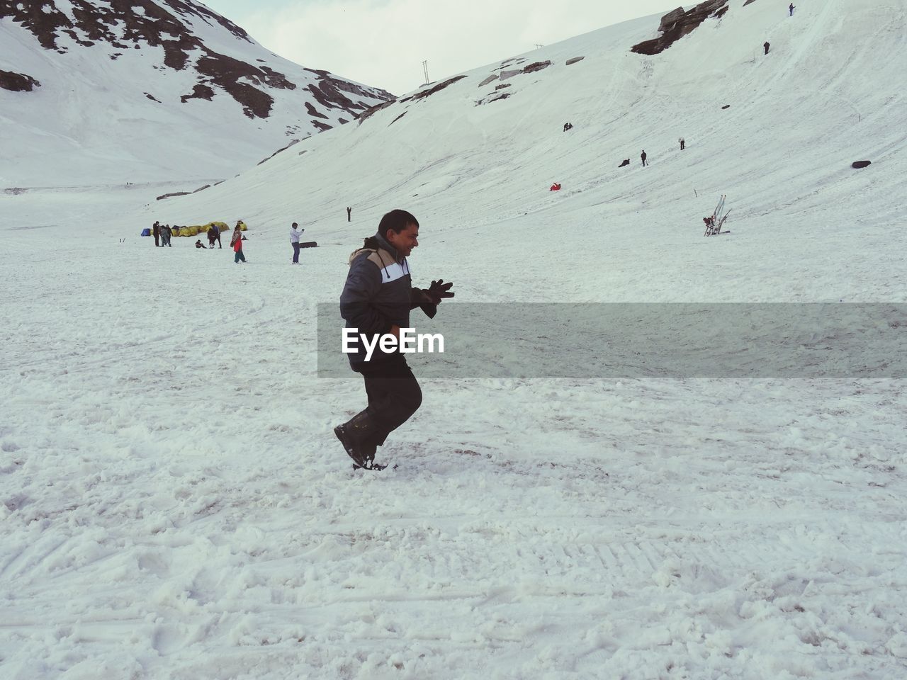 Side view of mature man walking on snow covered field