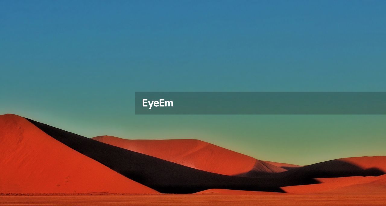 Scenic view of sand dunes against clear blue sky at namib desert