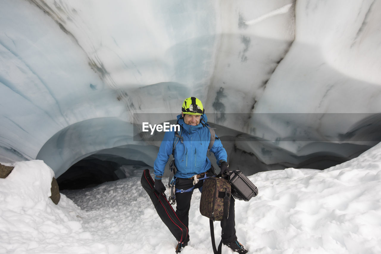 Scientist carries video gear from glacier cave for climate research