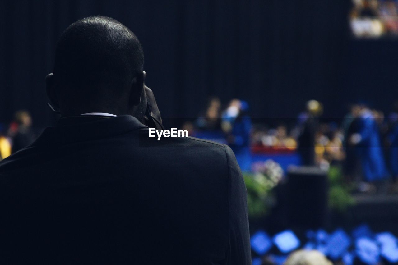 Rear view of man at graduation ceremony in school building