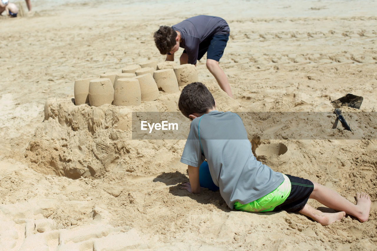 sand, land, beach, men, childhood, child, nature, leisure activity, lifestyles, adult, day, full length, vacation, trip, person, holiday, casual clothing, clothing, sandcastle, two people, togetherness, relaxation, family, outdoors, summer