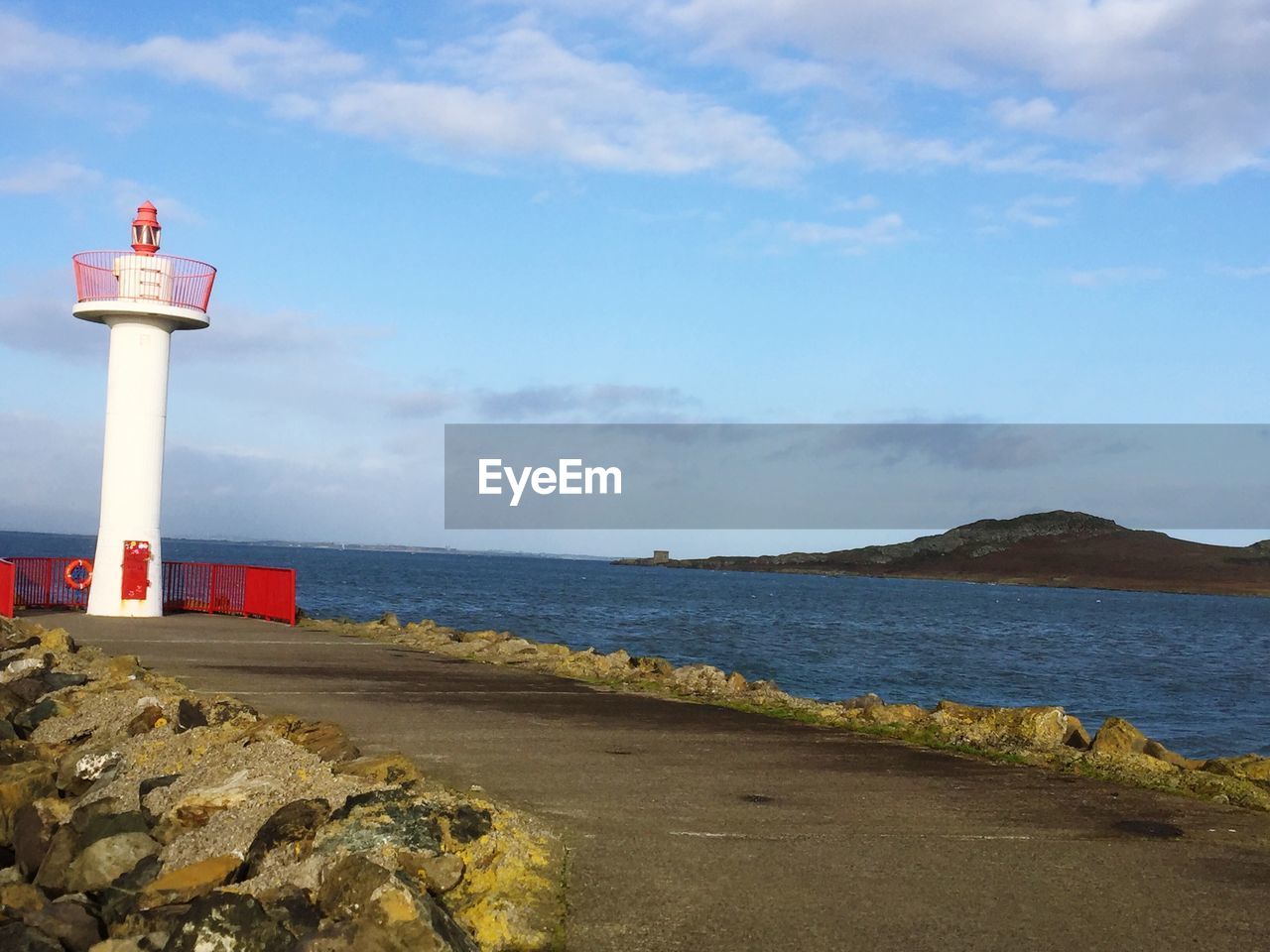 LIGHTHOUSE BY SEA AGAINST BUILDINGS