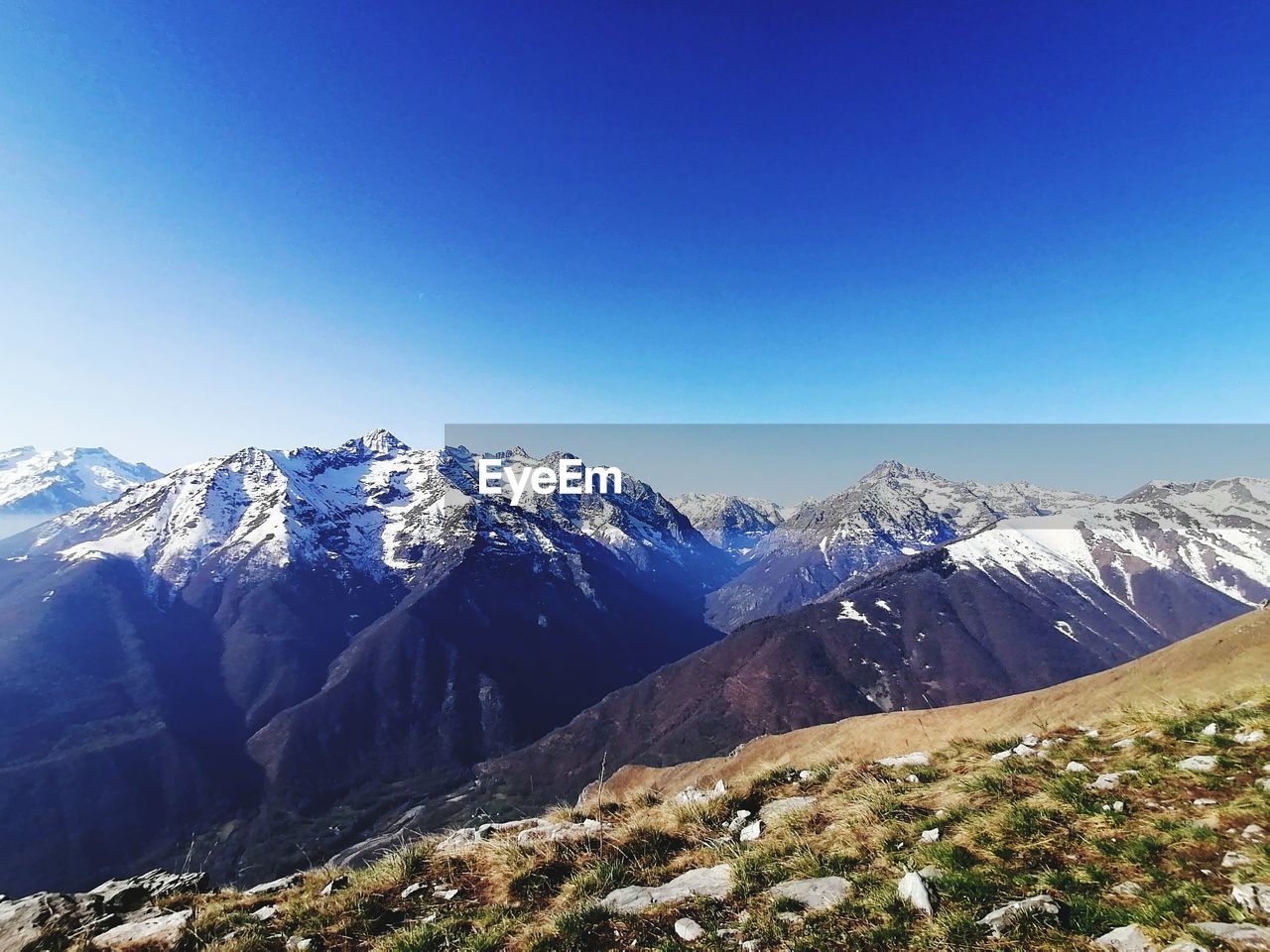 Scenic view of snowcapped mountains against clear blue sky