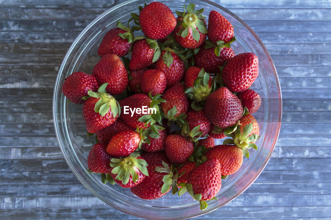 Strawberries on bowl on  blue wooden table