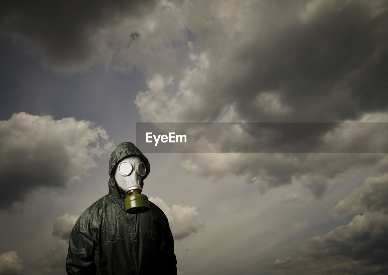 low angle view of man wearing hat against cloudy sky