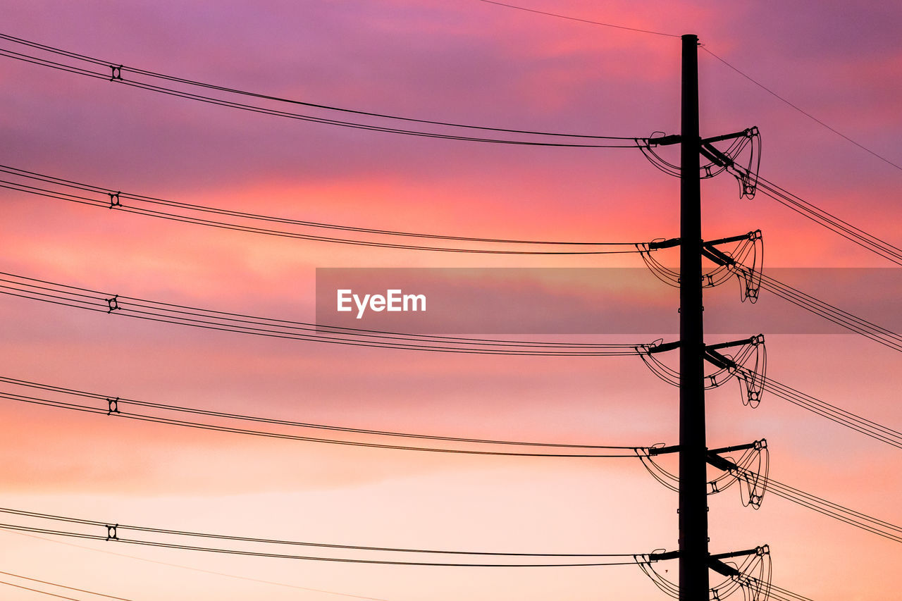 Low angle view of electricity pylon against pink sky during sunset