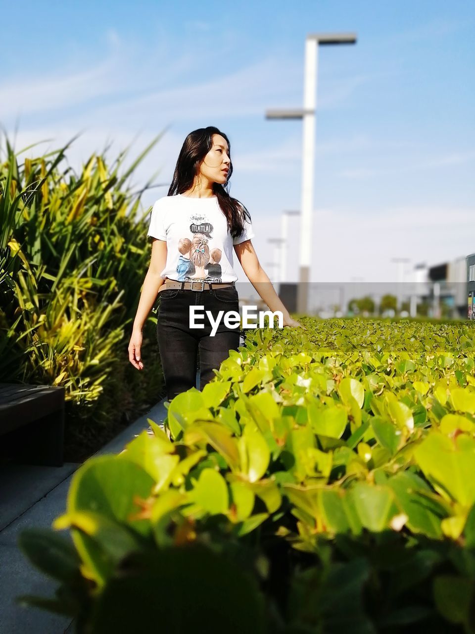 WOMAN STANDING BY FLOWERS AGAINST PLANTS