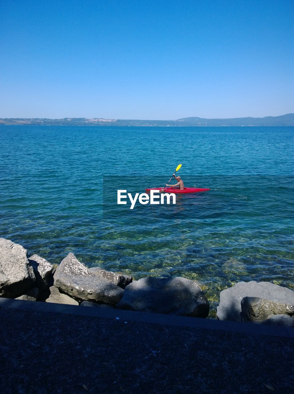 Man kayaking in sea against clear blue sky