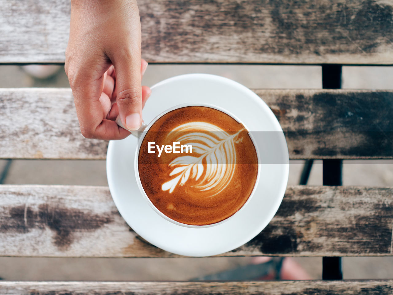 Cropped hand holding coffee cup on wooden table