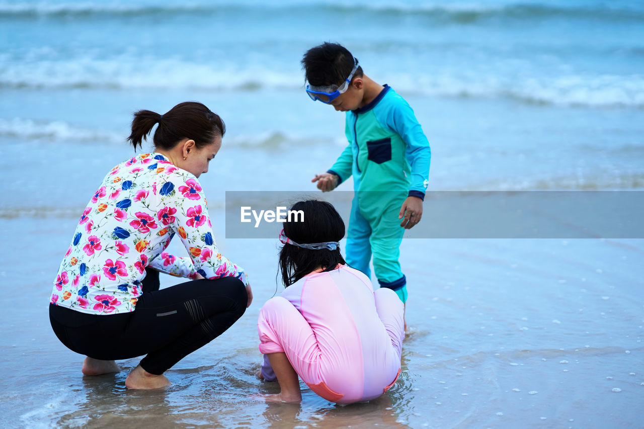 Rear view of people on sea shore beach 