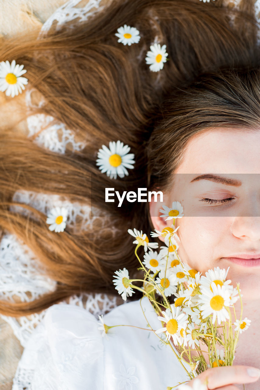 High angle view of woman lying on bed while holding flowers