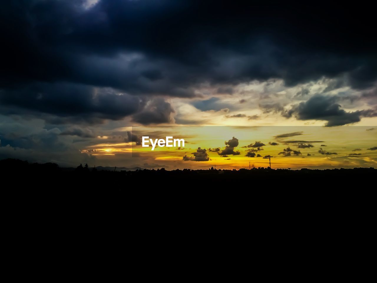 Silhouette landscape against dramatic sky during sunset