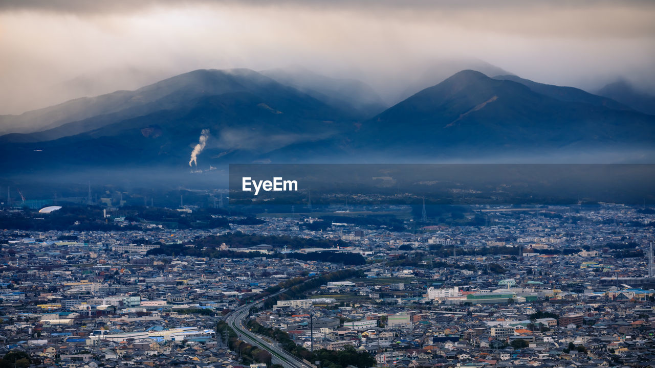 Dramatic and dark process cityscape in a strom and smog layer mountain background in japan