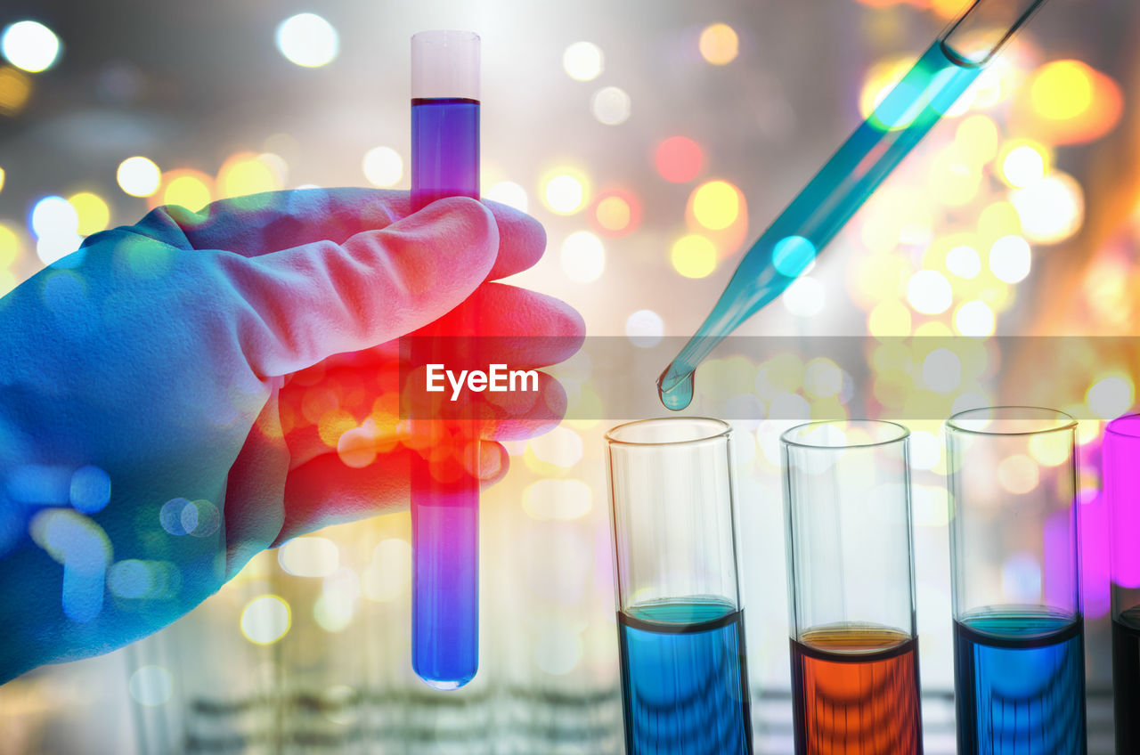 Cropped hand of scientist examining blue chemical in laboratory