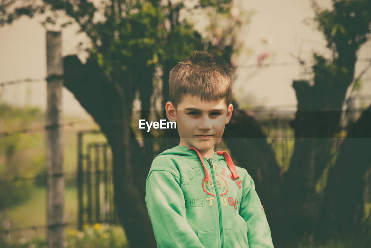 Close-up of boy standing against trees