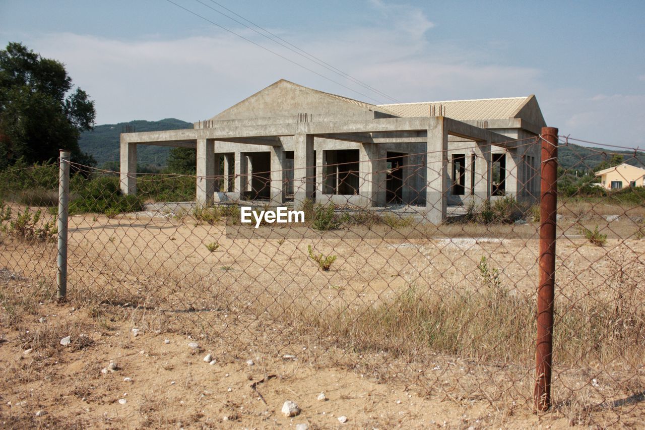 architecture, built structure, building exterior, building, home, sky, fence, house, landscape, rural area, abandoned, nature, no people, rural scene, rundown, cloud, estate, land, plant, day, outdoors, residential district, grass, farm, entrance, shack, residential area, wire, security, old, history, non-urban scene, metal