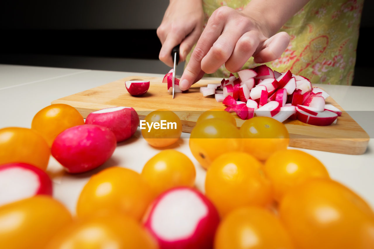 hand, food, indoors, one person, food and drink, fruit, women, childhood, child, healthy eating, lifestyles, multi colored, freshness, adult, vegetable, domestic room, domestic life, produce, wellbeing, selective focus, female, tomato, table, kitchen, home, close-up, holding, home interior, domestic kitchen, large group of objects, yellow
