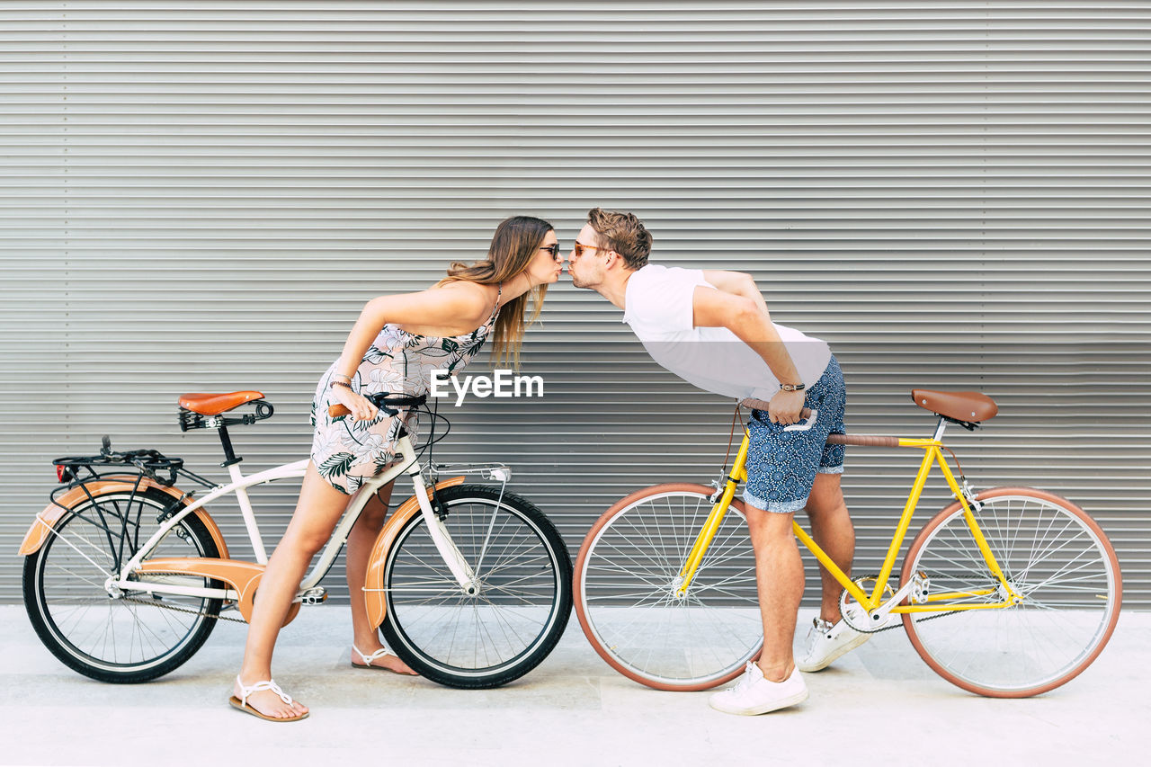 Side view of couple with bicycles kissing outdoors