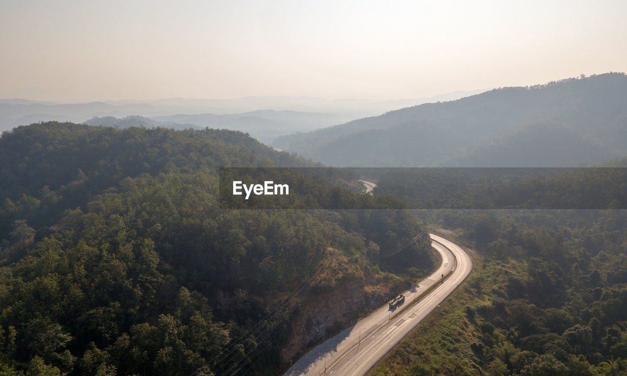 HIGH ANGLE VIEW OF ROAD AMIDST TREES AGAINST SKY