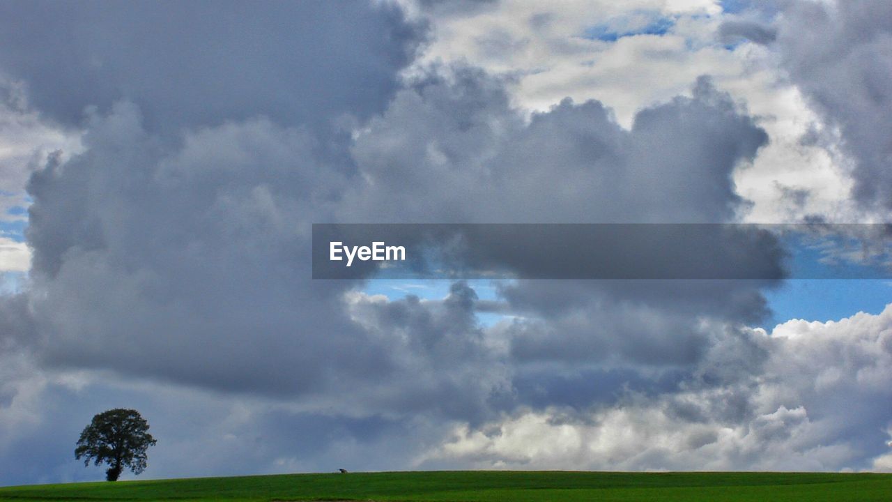 Scenic view of green landscape against cloudy sky