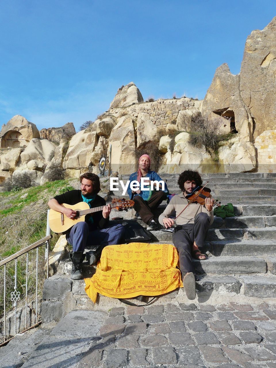 Musicians practicing on steps against clear blue sky