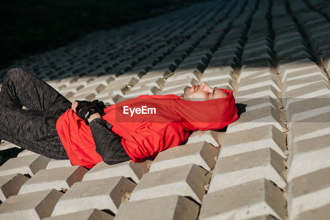 Young man in red hoodie. lying under the sun. unusual texture.