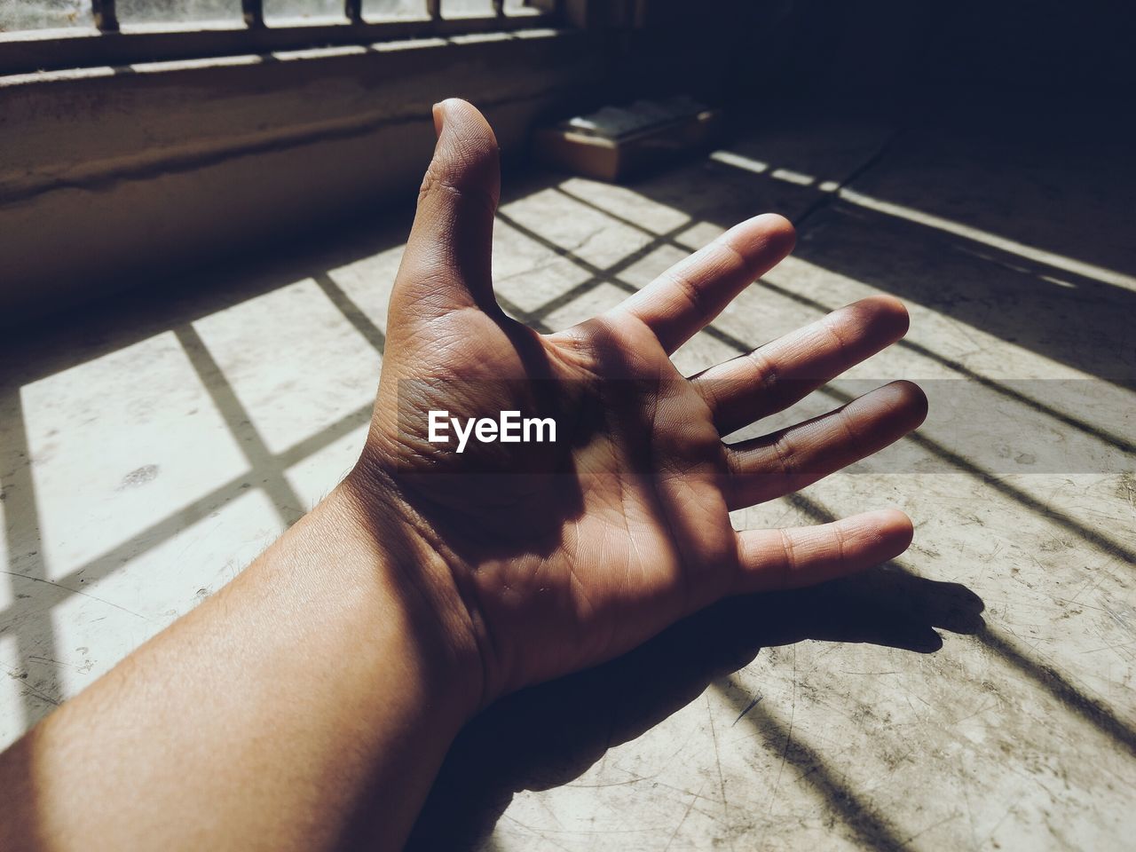 Close-up of human hand in shadow of window