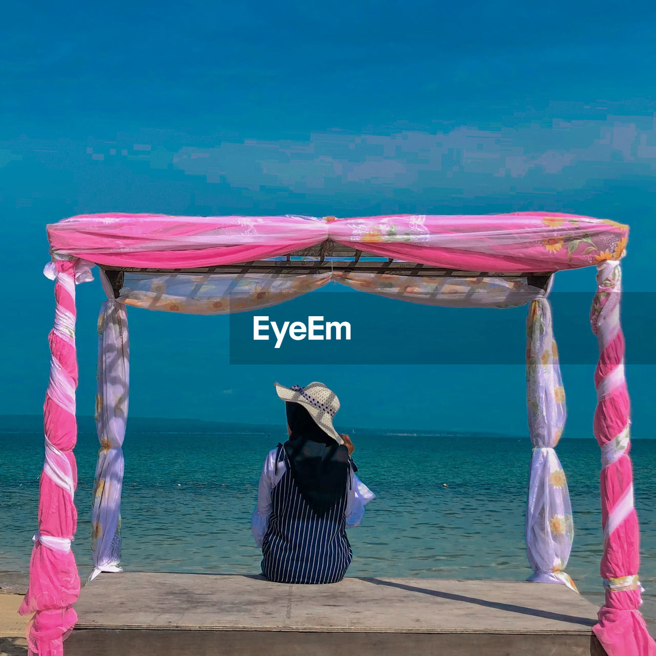 Rear view of woman with umbrella on beach against sky