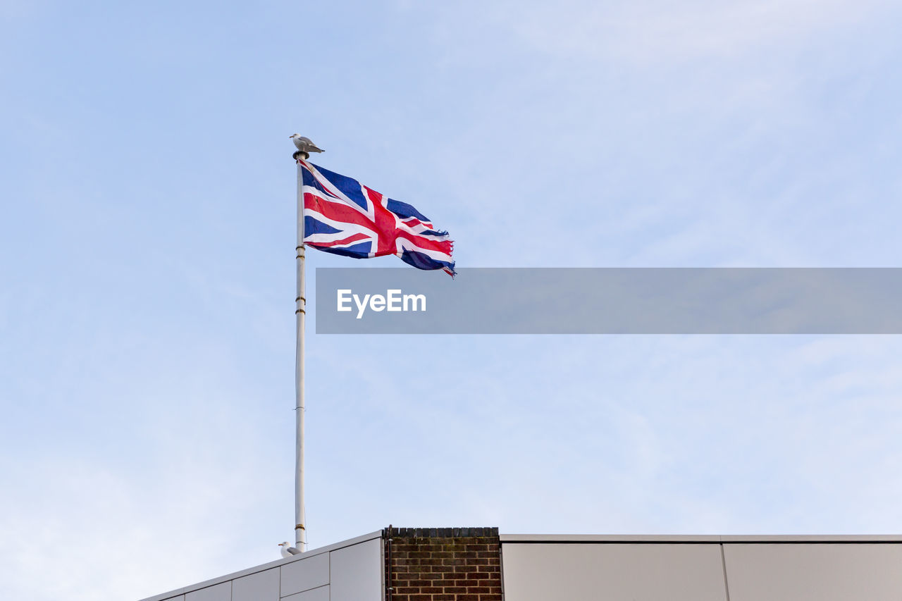 Flag of the united kingdom, flag of england embroidered on blue sky on the roof of a building.