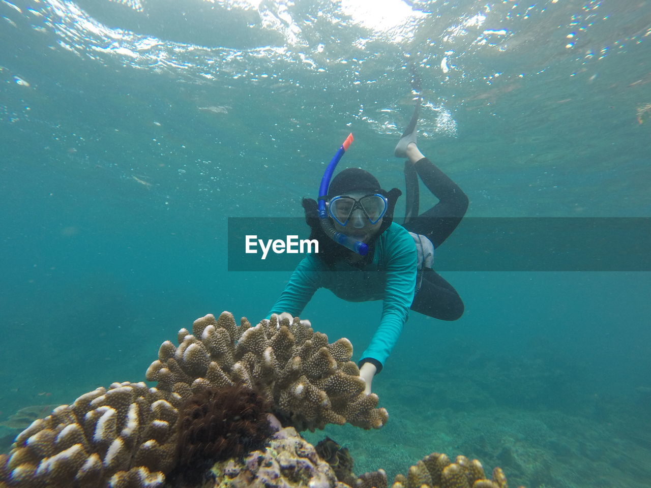 Portrait of woman wearing scuba mask while swimming underwater