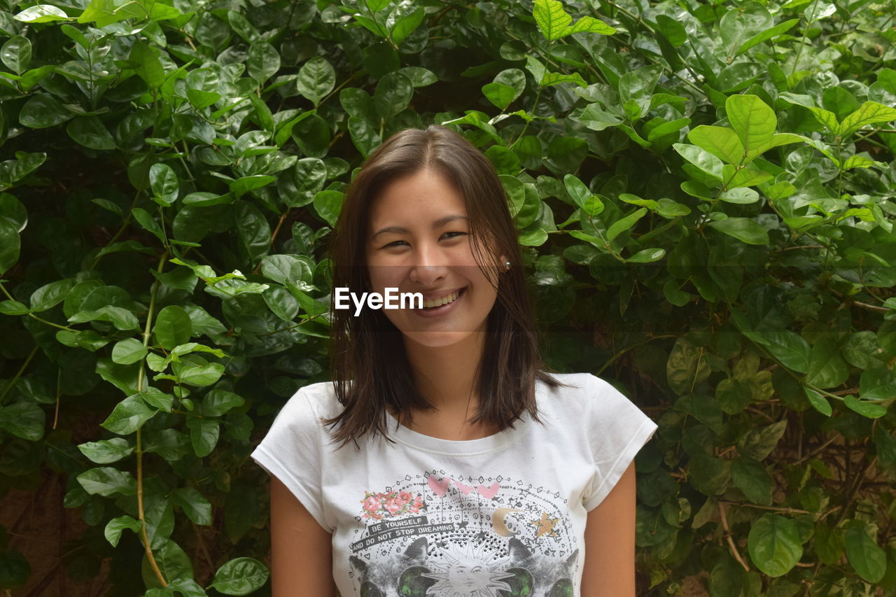 PORTRAIT OF SMILING YOUNG WOMAN OUTDOORS